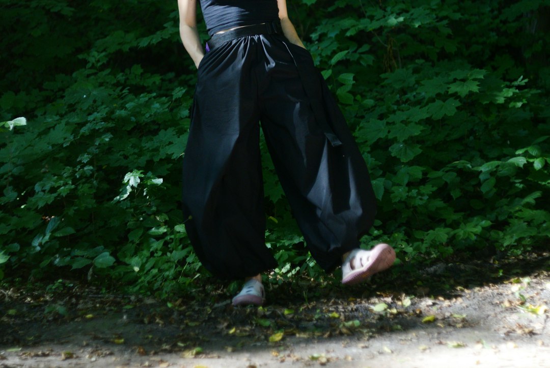 A person's legs in black baggy pants and pink shoes