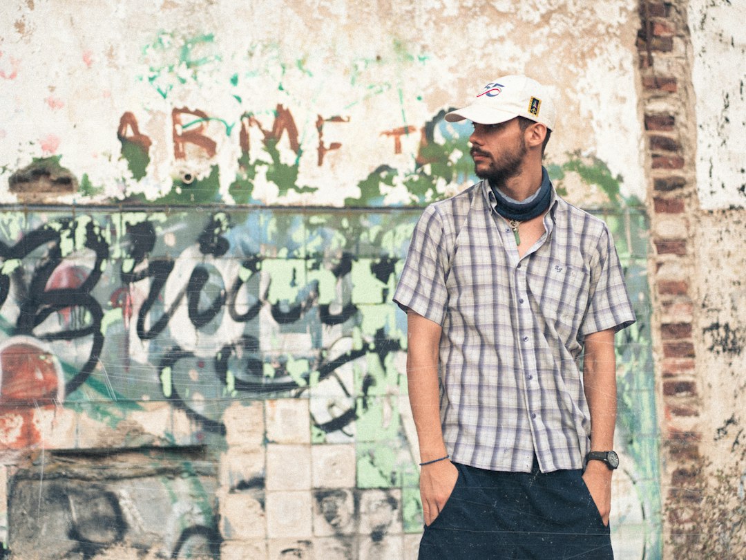 a man standing in front of a graffiti covered wall